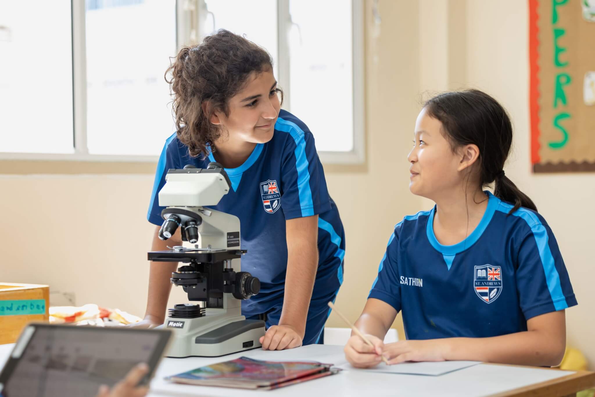 Two pupils using a microscope in a St. Andrews Sathorn classroom